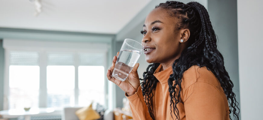 Young woman drinking water at home